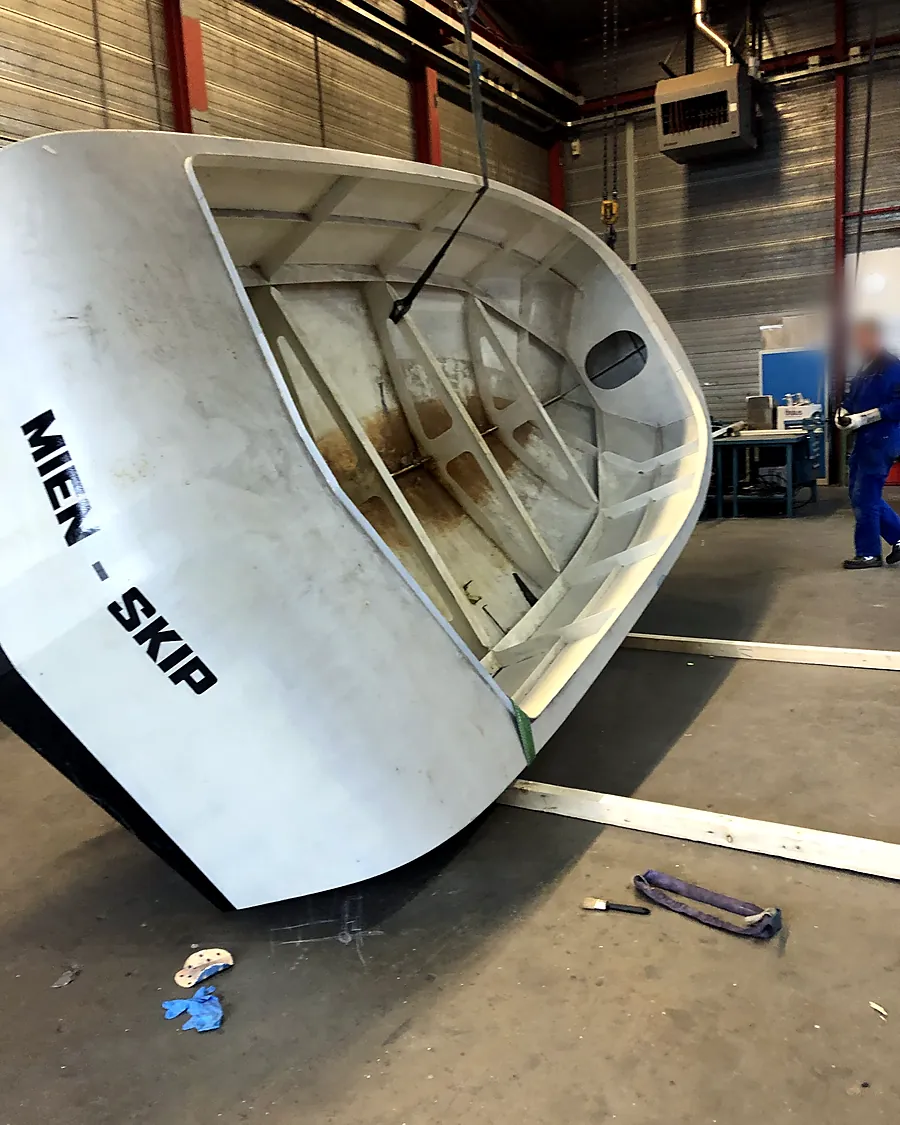 Stalen casco van de sloep aan de takel in de werkplaats