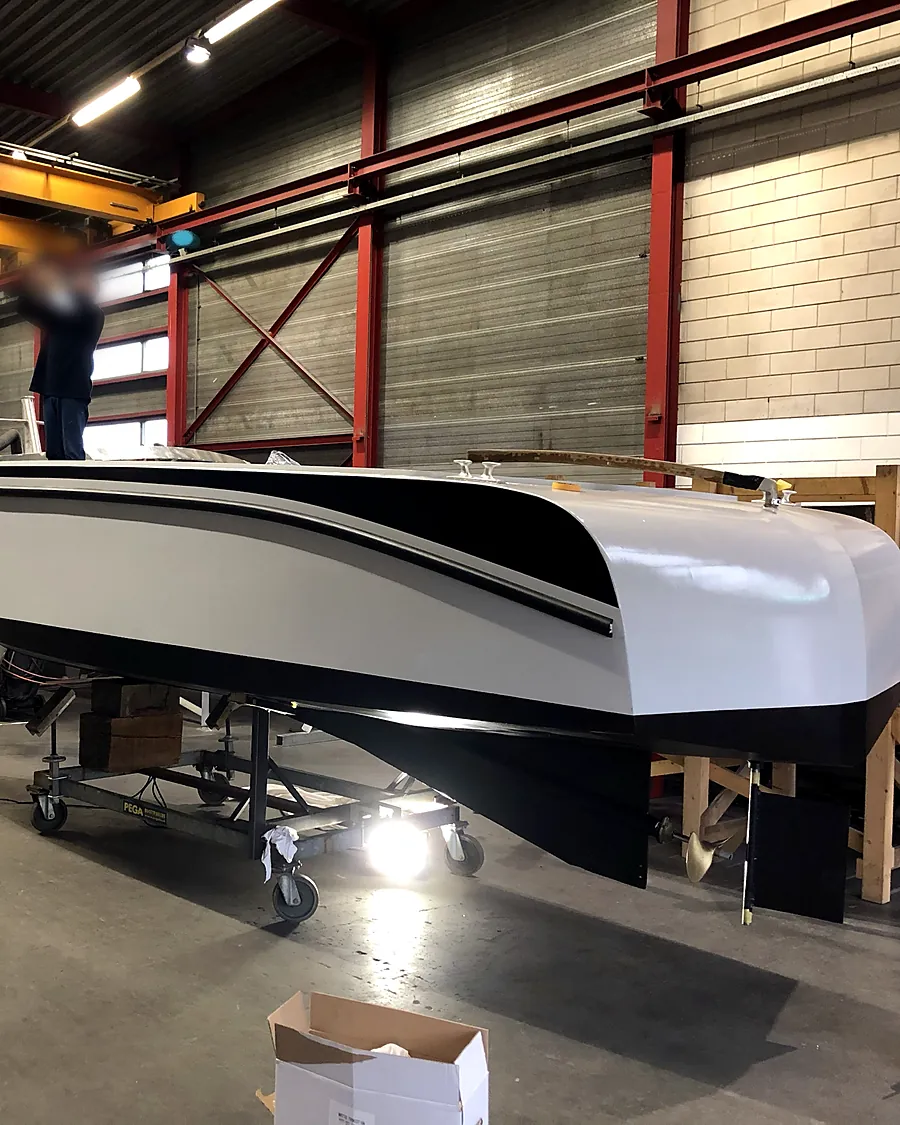 De sloep in de werkplaats na het schilderwerk in wit, grijs en zwart